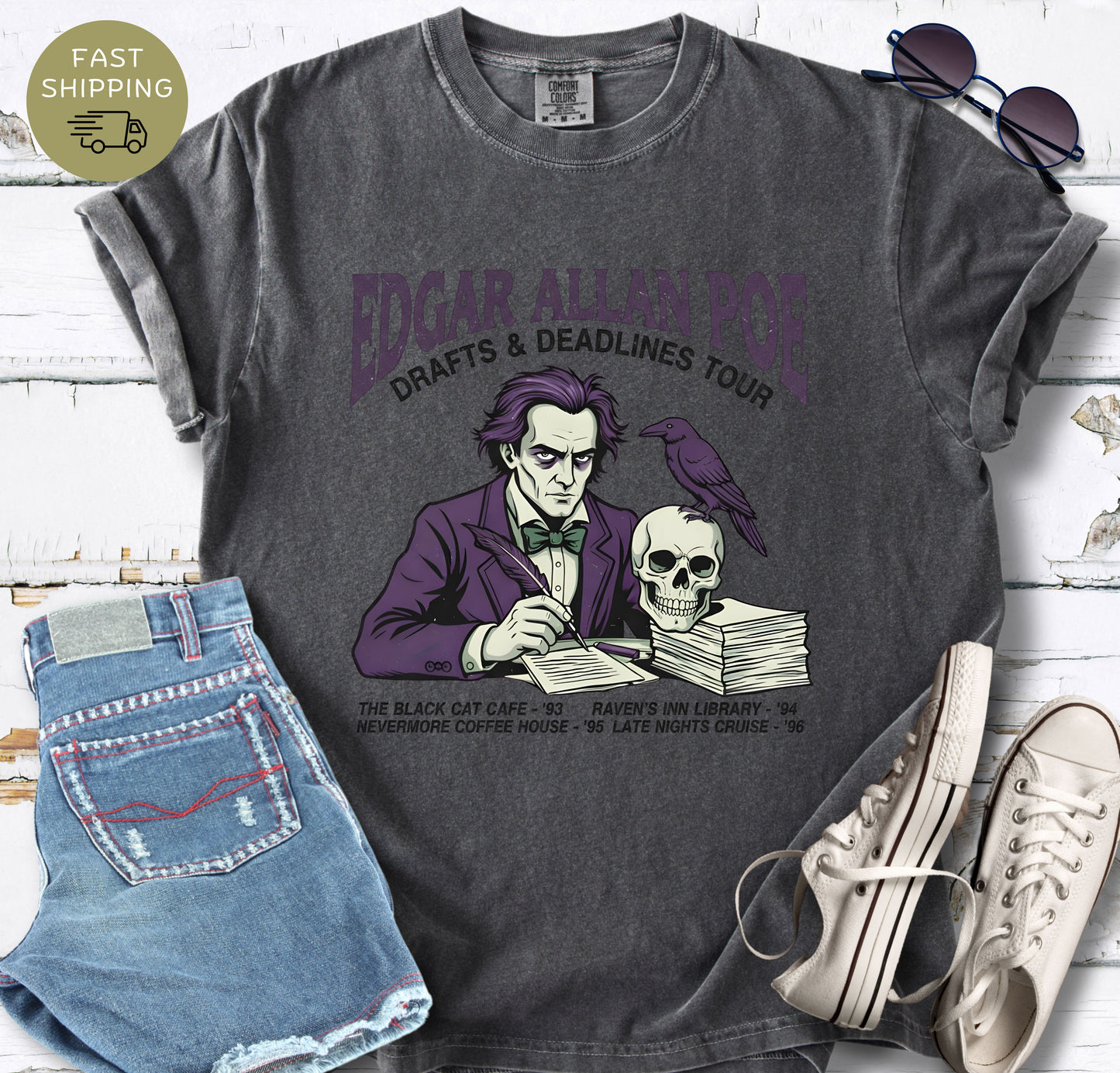 Pepper t-shirt with Illustrated Edgar Allan Poe wearing a purple suit, writing at a desk with a raven and skull, styled like a vintage literary tour t-shirt design.
