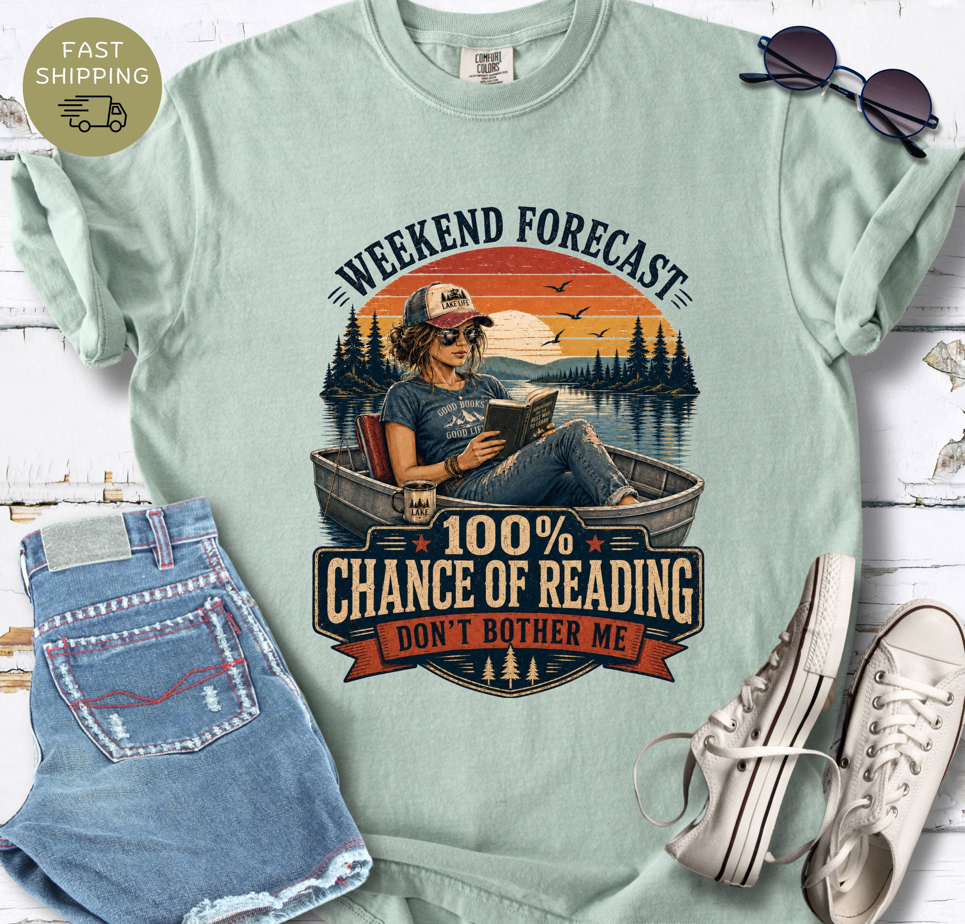 Summer reading T-shirt with a woman in sunglasses reading in a boat and the words “Don’t Bother Me.”