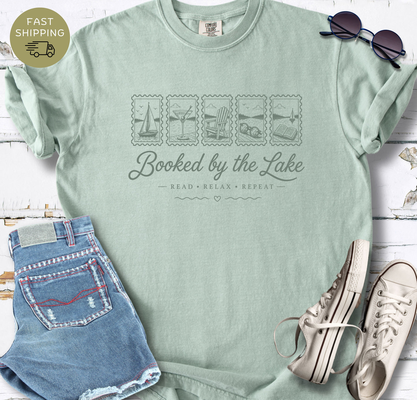 Lake reader gift shirt featuring “Booked by the Lake” and small illustrated lake life icons.