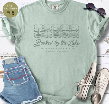 Lake reader gift shirt featuring “Booked by the Lake” and small illustrated lake life icons.