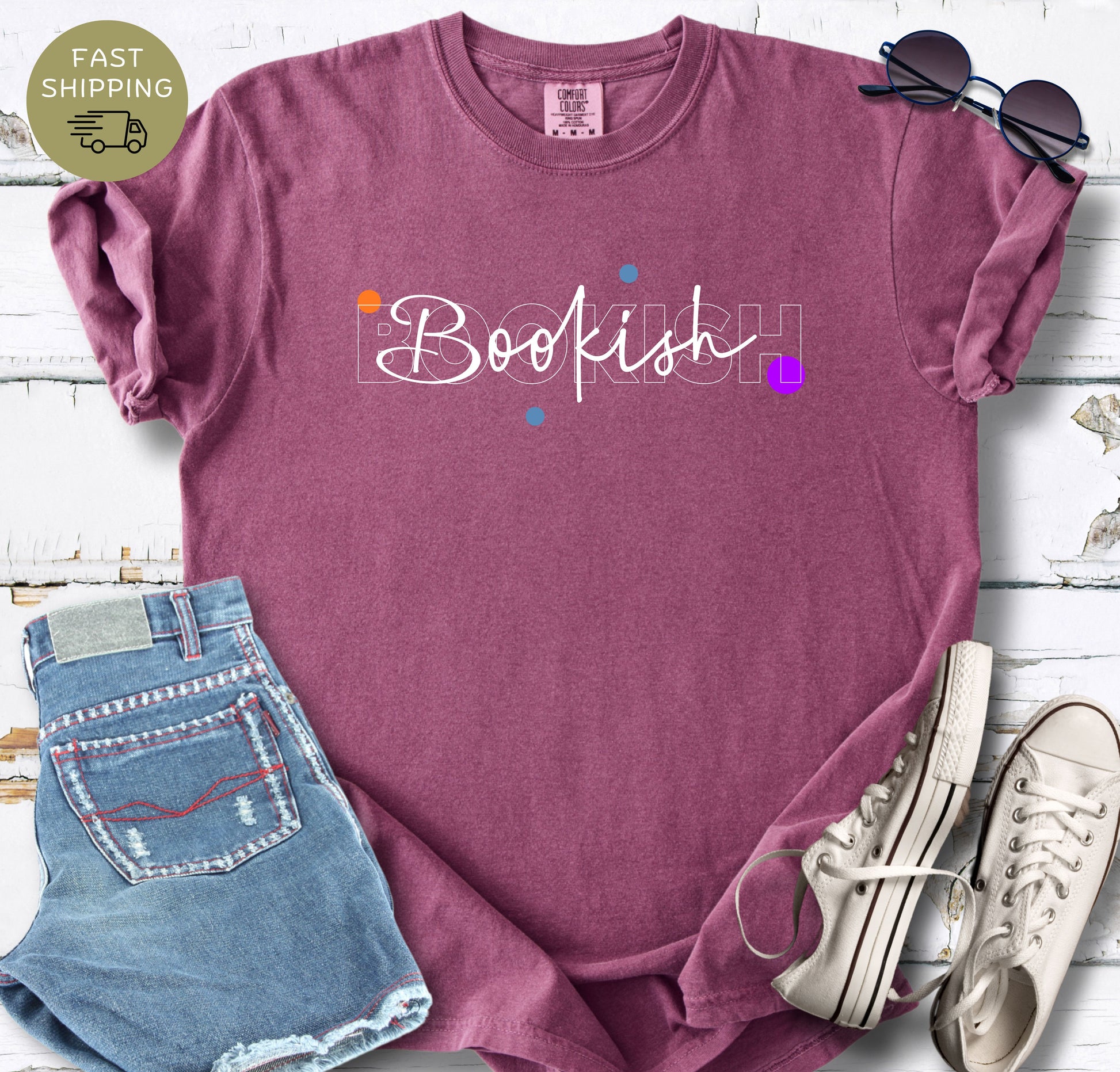 Minimalist book lover graphic tee with white lettering and colourful accent dots on a berry 
shirt.