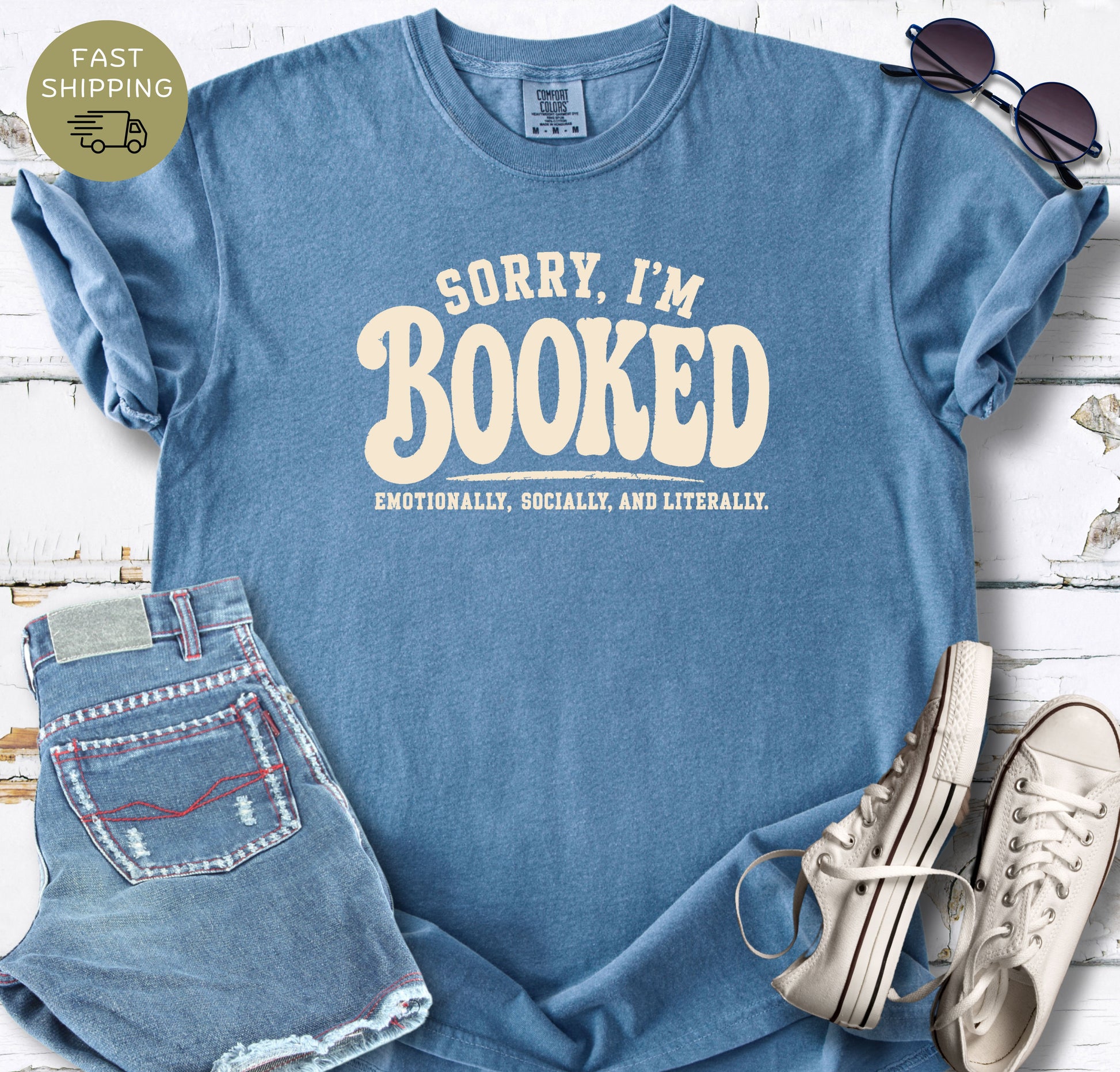 Bookish graphic tee styled flat lay with jeans, sneakers, and sunglasses.