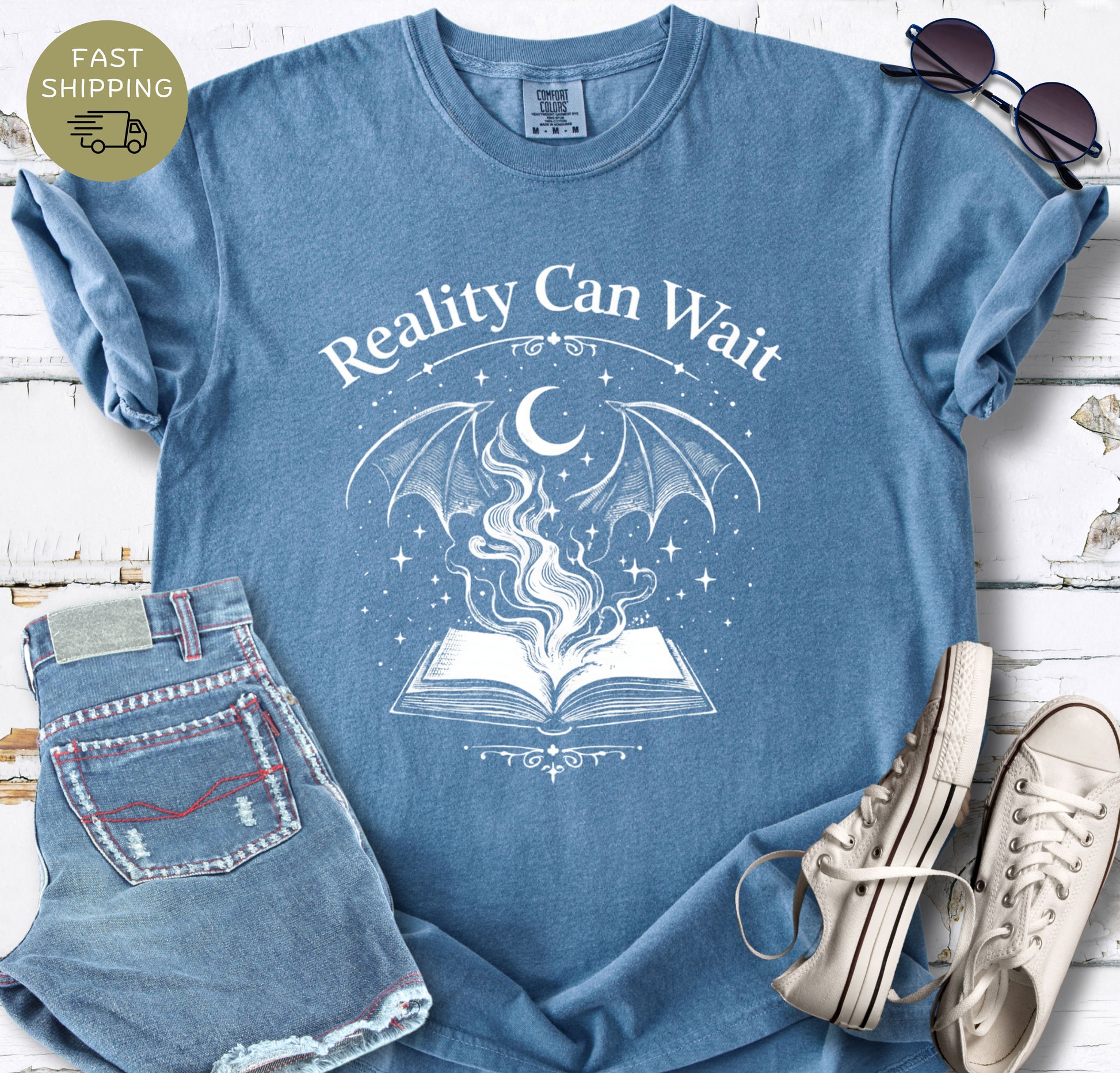Reality Can Wait fantasy bookish t-shirt with open book and magical design on Comfort Colors 1717 bue jeans