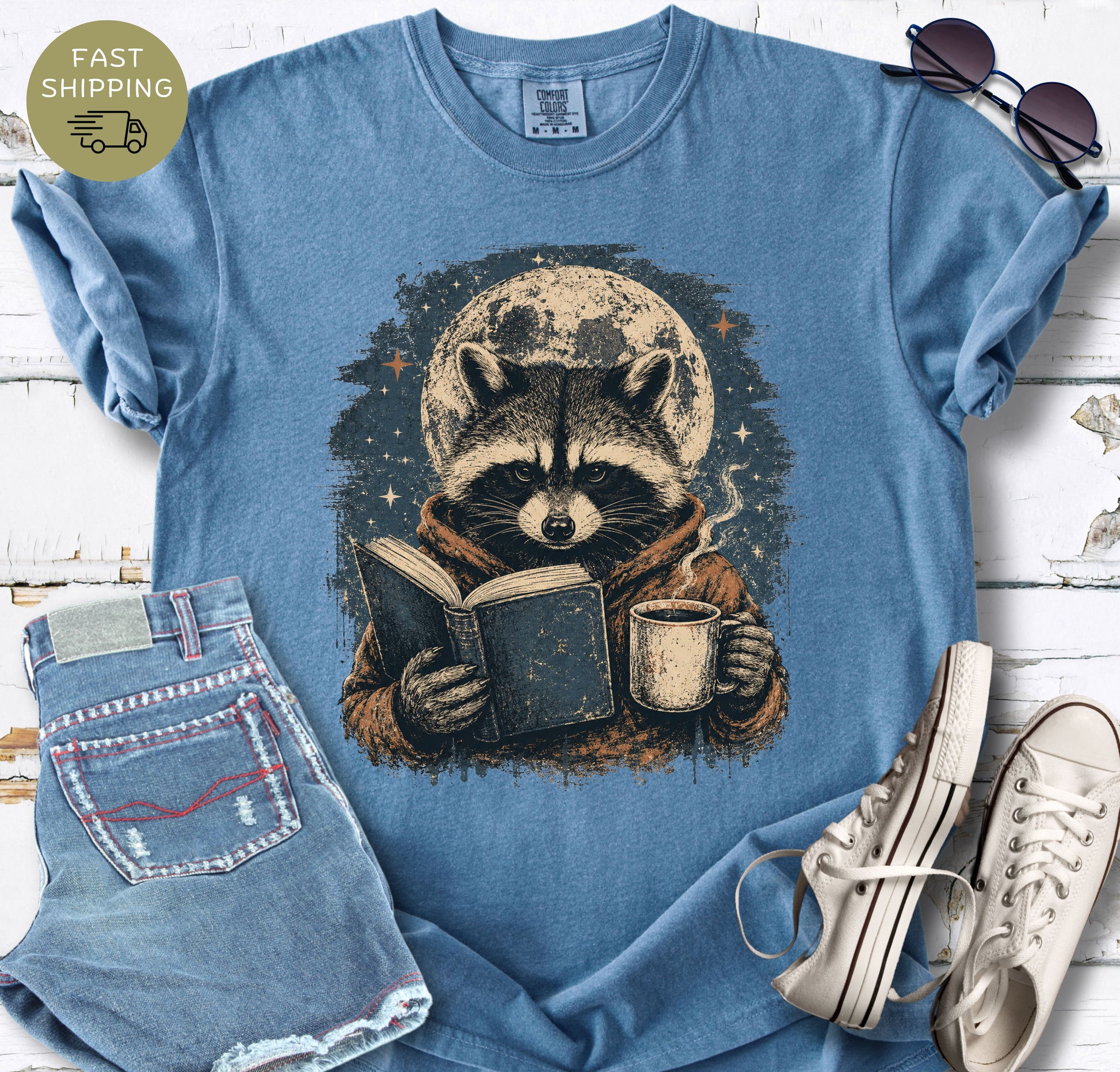 Blue Jean Comfort Colors shirt with a moonlit raccoon reading design.