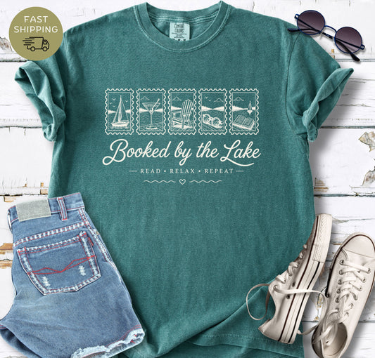 Blue Spruce Comfort Colors T-shirt featuring the phrase “Booked by the Lake” and “Read Relax Repeat.”