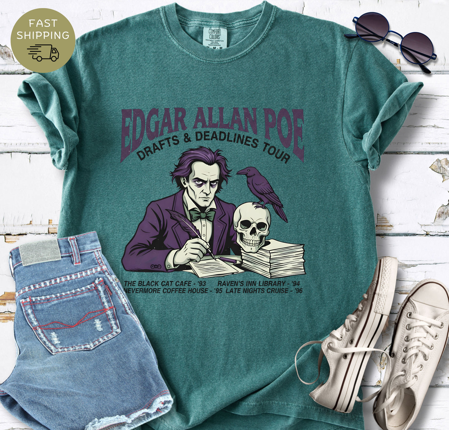 Blue Spruce shirt Illustrated Edgar Allan Poe wearing a purple suit, writing at a desk with a raven and skull, styled like a vintage literary tour t-shirt design.