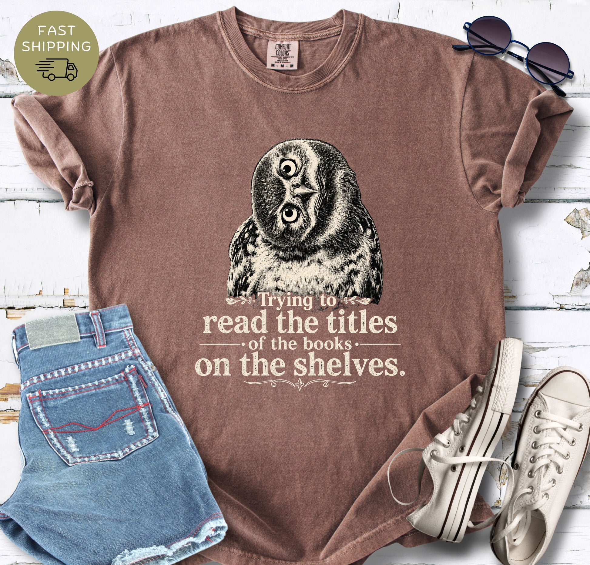 Reader gift shirt featuring a tilted owl illustration and the quote “Trying to read the titles of the books on the shelves.”