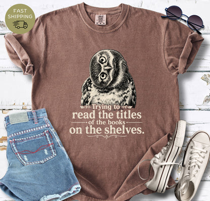 Reader gift shirt featuring a tilted owl illustration and the quote “Trying to read the titles of the books on the shelves.”