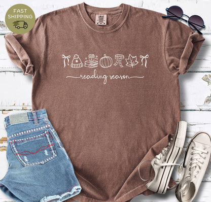 Reading season graphic tee with cozy autumn symbols on an espresso garment-dyed shirt.