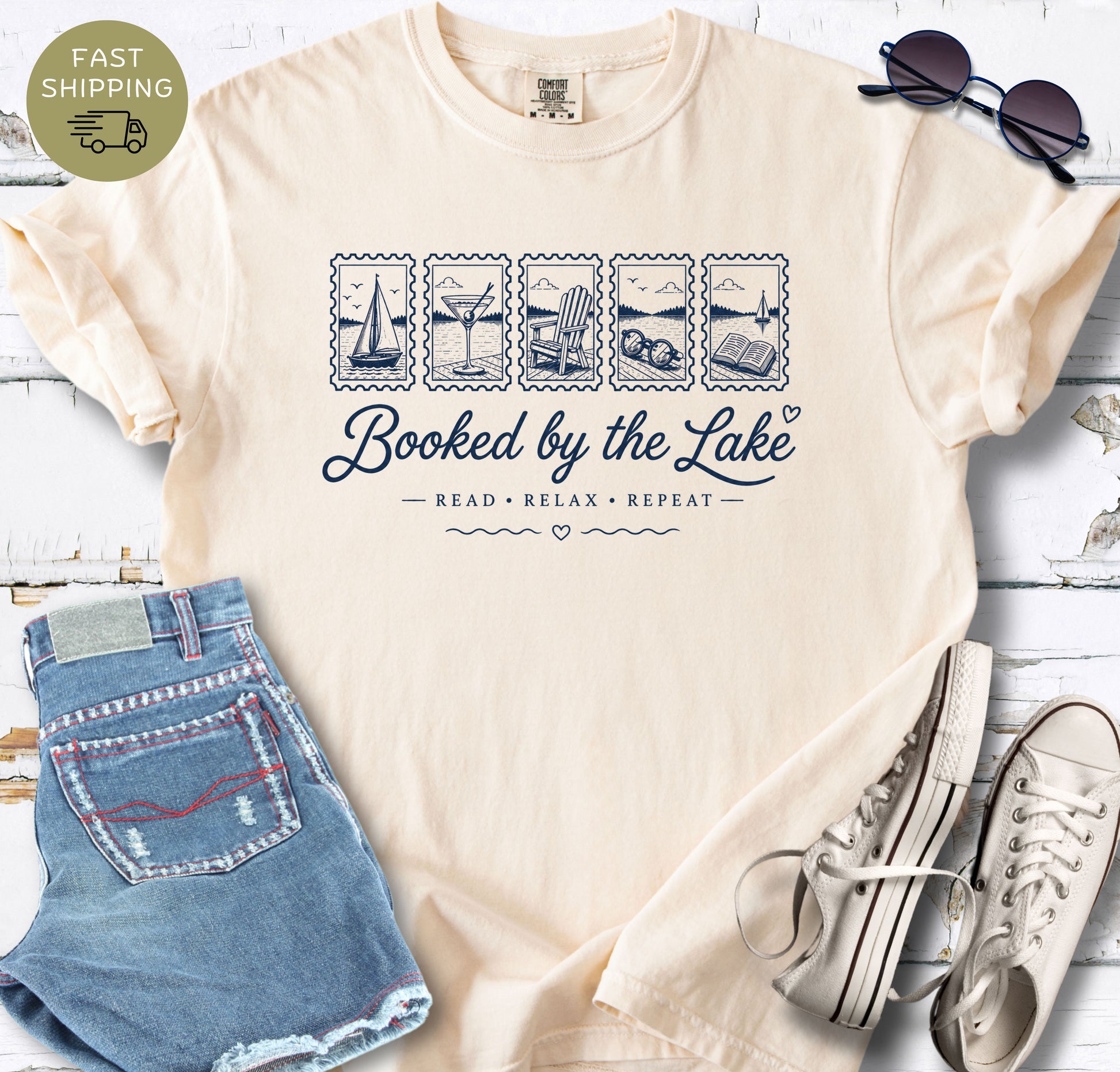 Book lover lake shirt with white postage-stamp illustrations of a sailboat, drink, chair, sunglasses and open book.