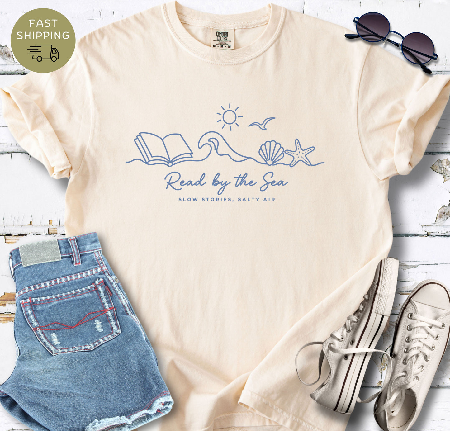 Ivory bookish t-shirt with “Read by the Sea” coastal design