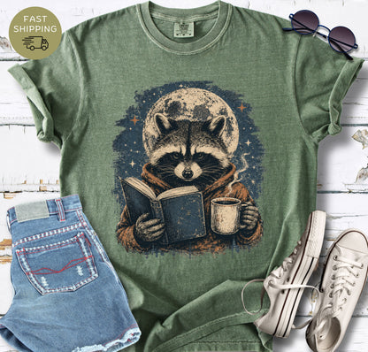 Cosy reader t-shirt featuring a raccoon holding a book and coffee beneath the moon.