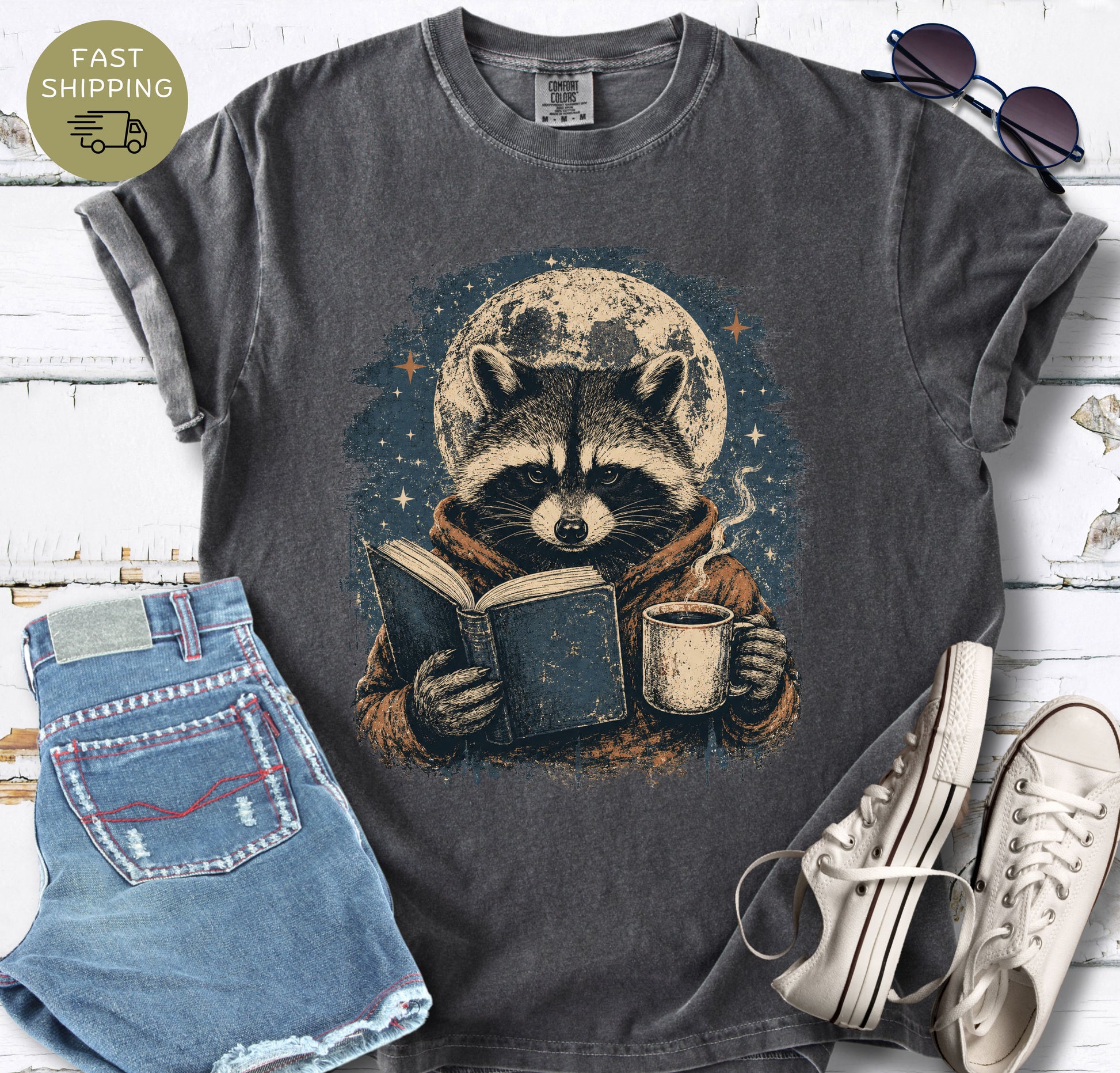 Bookish raccoon graphic tee with a hot drink, stars, and vintage distressed artwork.