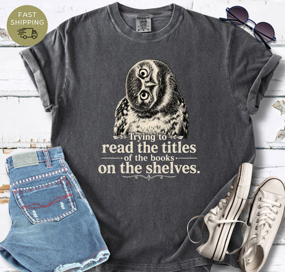 Pepper Comfort Colors T-shirt featuring an owl illustration and the phrase “Trying to read the titles of the books on the shelves.”